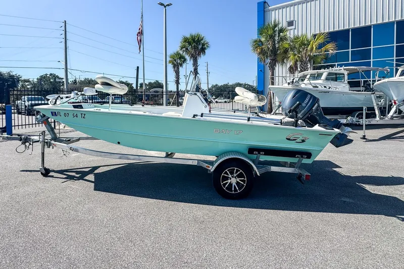 Slide: The Image of 2023 G3 Bay 17 boat on trailer, parked outdoors near palm trees and a building. - 7