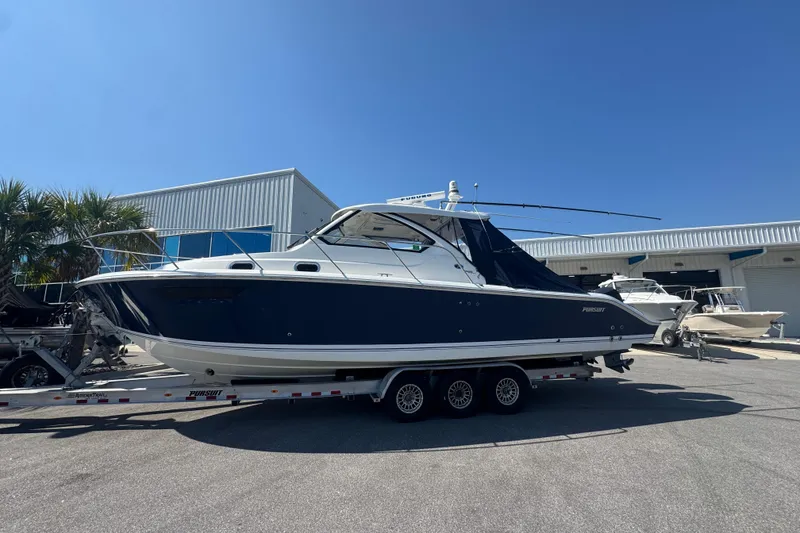 The Image of 2020 Pursuit OS 325 Offshore boat on trailer, parked outdoors under clear blue sky. - 0