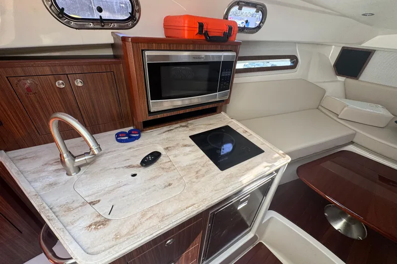 Slide: The Image of 2020 Pursuit OS 325 Offshore boat interior with kitchenette, microwave, and seating area. - 10
