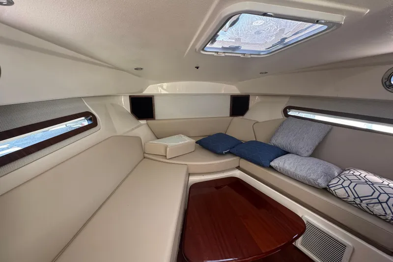 Slide: The Image of 2020 Pursuit OS 325 Offshore cabin interior with beige seating and decorative pillows. - 11