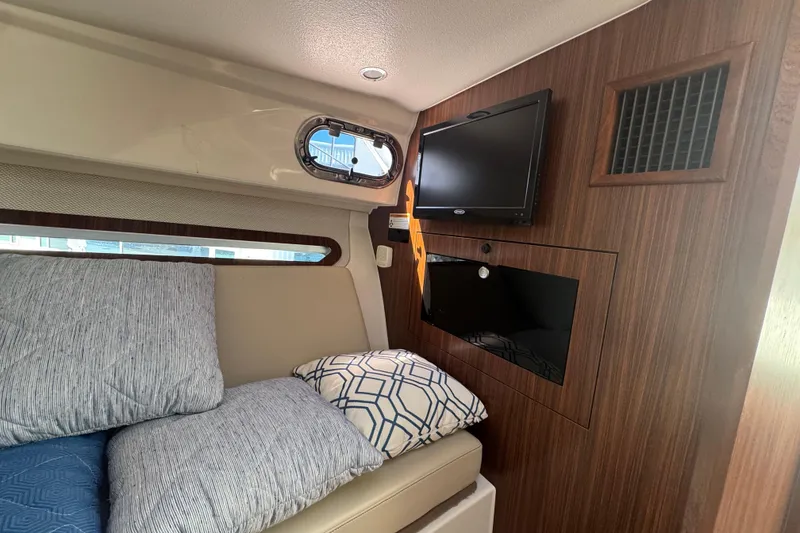 Slide: The Image of 2020 Pursuit OS 325 Offshore cabin interior with TV, cushions, and wood paneling. - 13