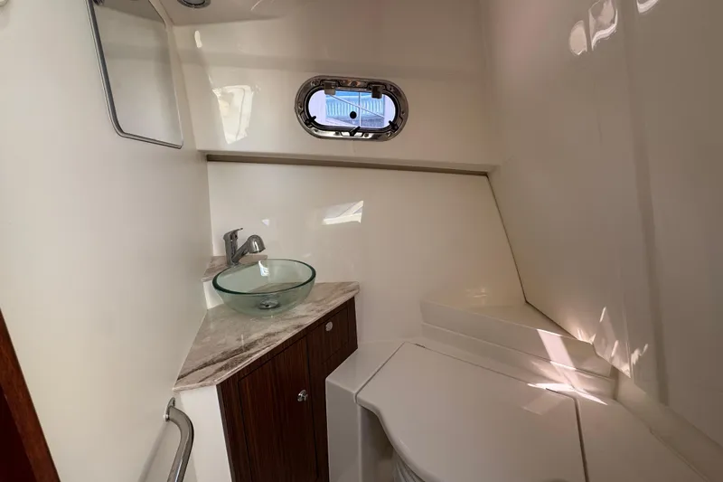 Slide: The Image of 2020 Pursuit OS 325 Offshore boat bathroom with glass sink and porthole window. - 14