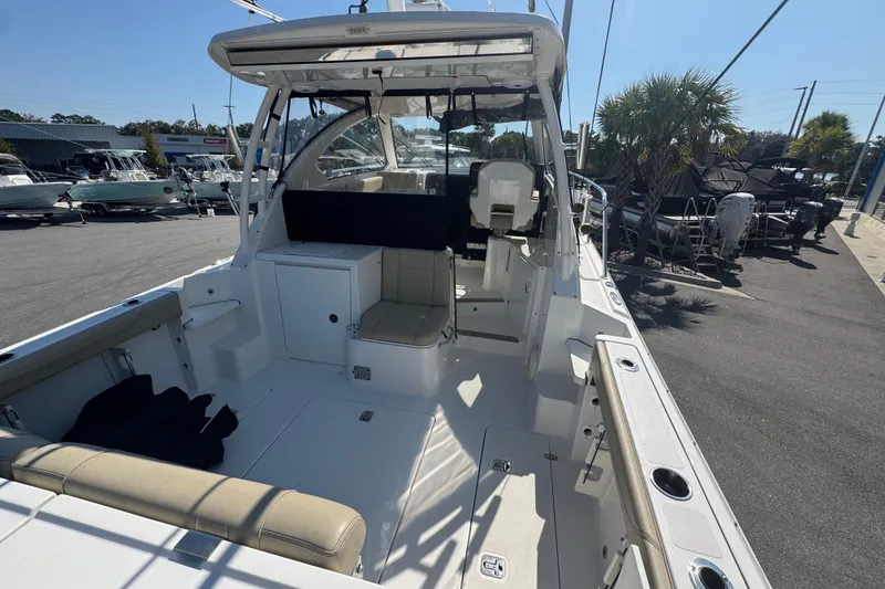 Slide: The Image of 2020 Pursuit OS 325 Offshore boat interior with seating and helm, docked under clear sky. - 3