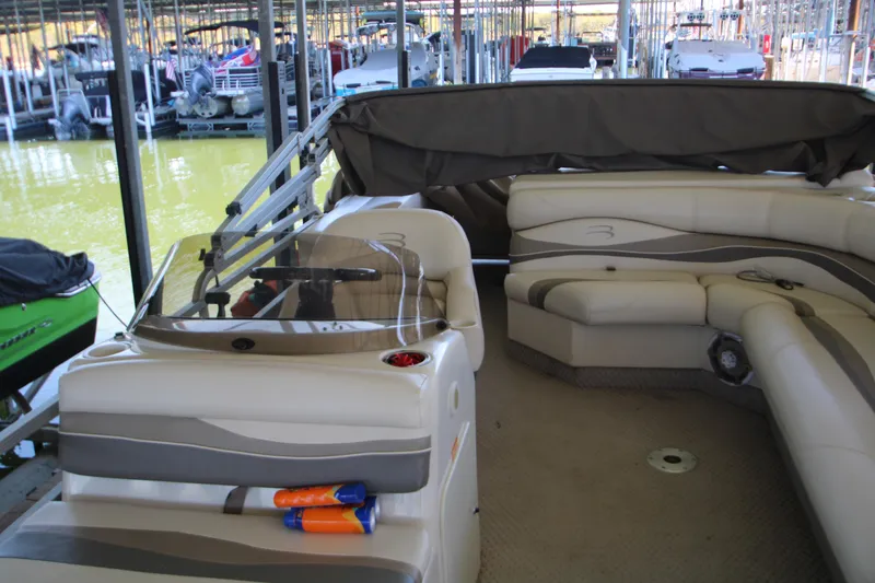 Slide: The Image of 2005 Bennington 2275FSi pontoon boat interior with beige seating, docked in marina. - 11