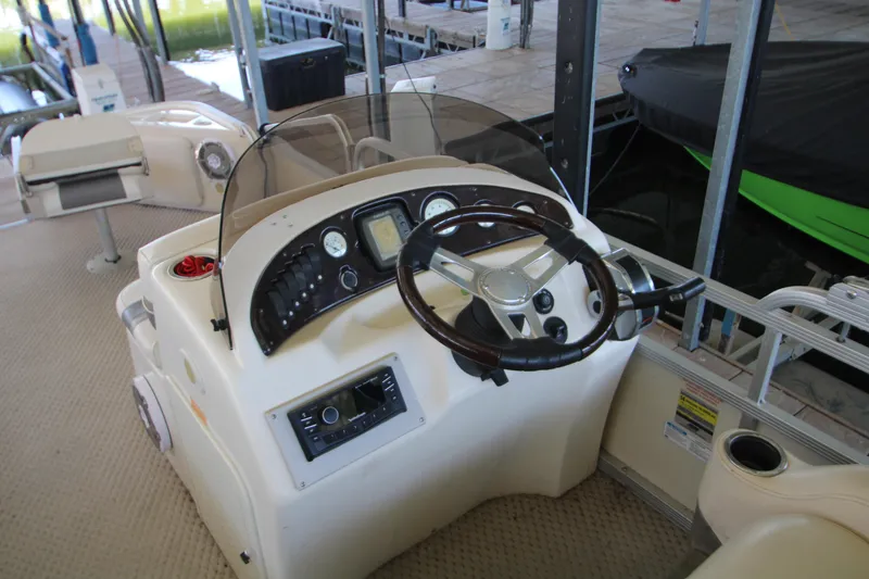 Slide: The Image of 2005 Bennington 2275FSi boat dashboard with steering wheel and controls in marina setting. - 14
