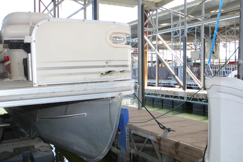Slide: The Image of 2005 Bennington 2275FSi pontoon boat with visible damage, docked in a marina. - 23