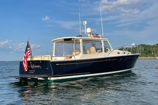 The Image of 2013 MJM 40z Express boat on water, American flag, clear sky background. - 0