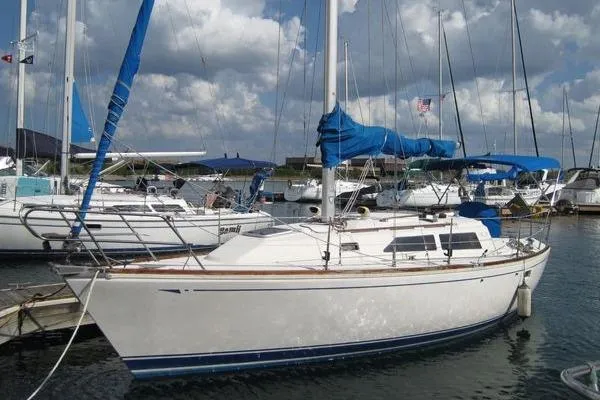 The Image of 1988 CAL 28 sailboat docked in a marina under a partly cloudy sky. - 0