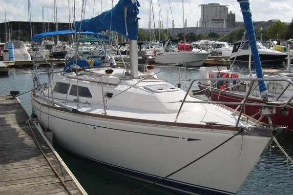 Slide: The Image of 1988 CAL 28 sailboat docked in marina, featuring blue sail covers and sleek white hull. - 1