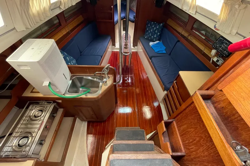 Slide: The Image of Interior of 1988 CAL 28 sailboat with wooden flooring, kitchenette, and seating area. - 22