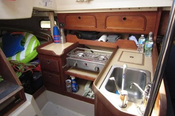 Slide: The Image of Interior of a 1988 CAL 28 sailboat galley with stove, sink, and storage. - 26