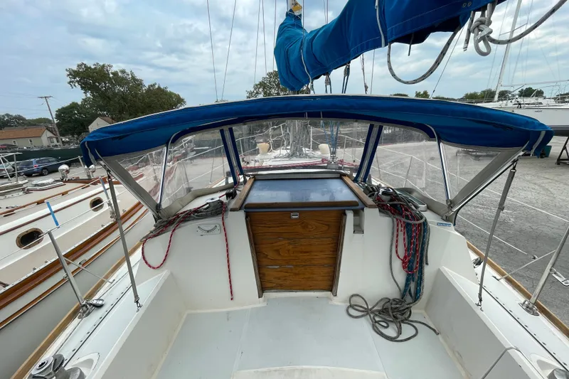 Slide: The Image of 1988 CAL 28 sailboat cockpit with blue canopy and ropes, docked in a marina. - 9