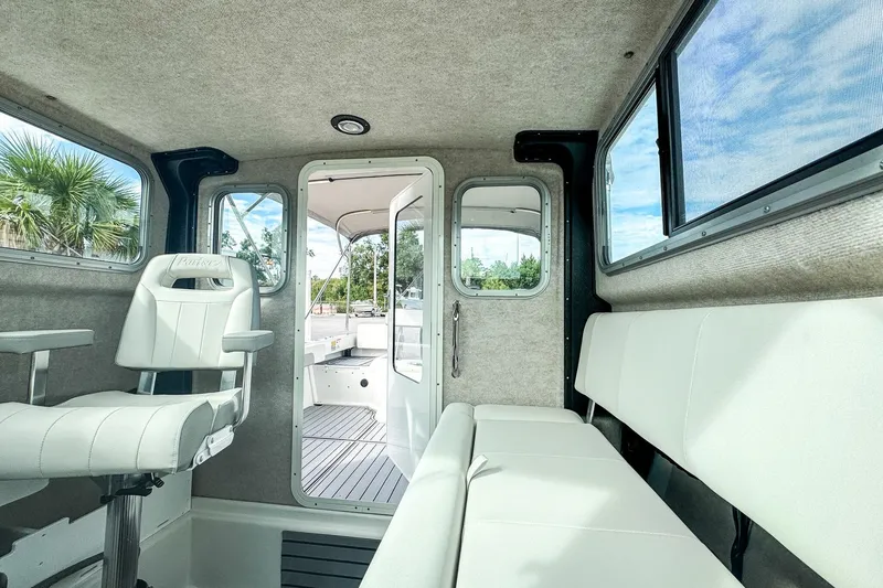 Slide: The Image of Interior of 2023 Parker 2120 Sport Cabin boat with white seating and windows. - 12