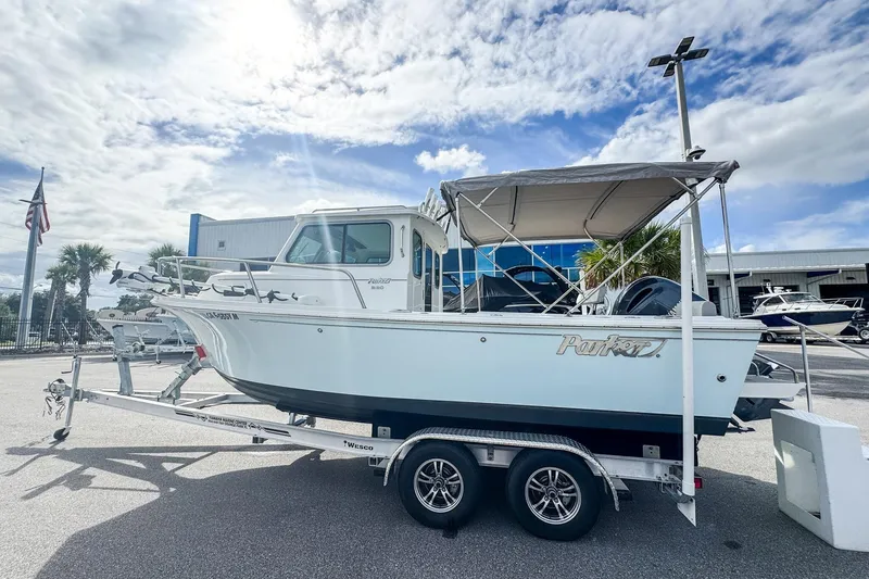 Slide: The Image of 2023 Parker 2120 Sport Cabin boat on trailer under cloudy sky. - 3