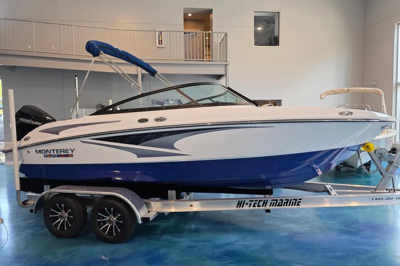 Slide: The Image of 2024 Monterey M-205 boat on trailer in showroom, blue and white design. - 2