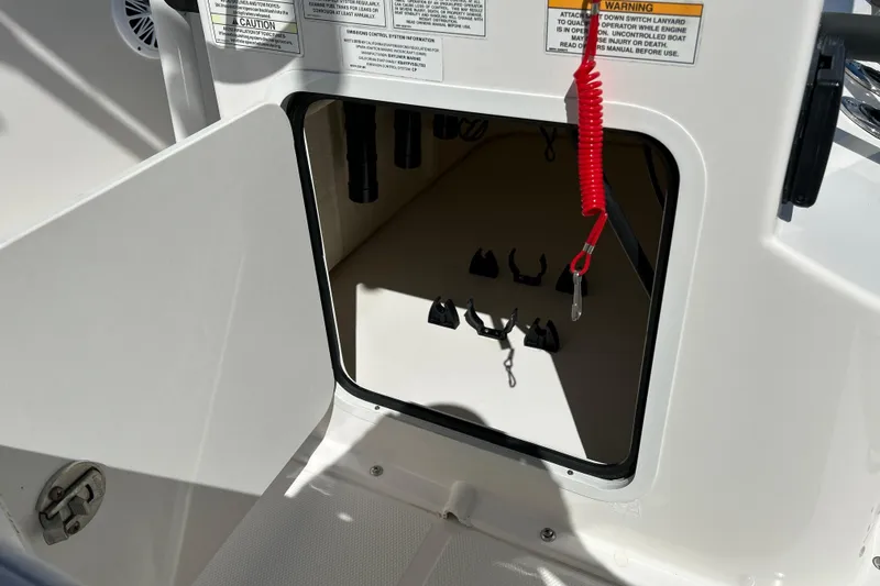 Slide: The Image of Open storage compartment on 2019 Bayliner Element F18 boat with safety warnings. - 16