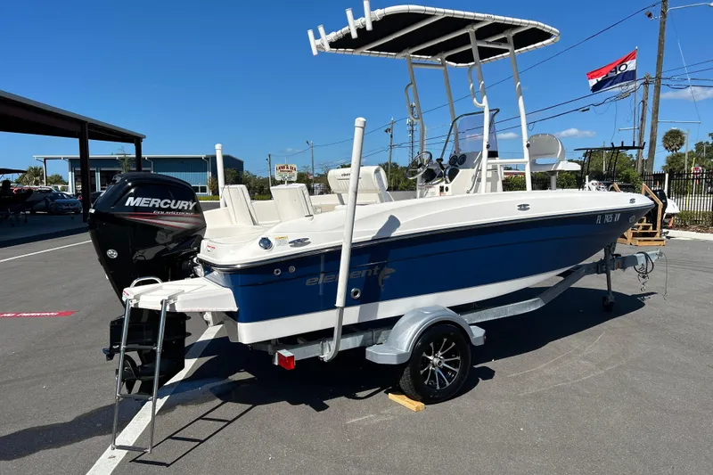 Slide: The Image of 2019 Bayliner Element F18 boat with Mercury engine on trailer, parked outdoors. - 2