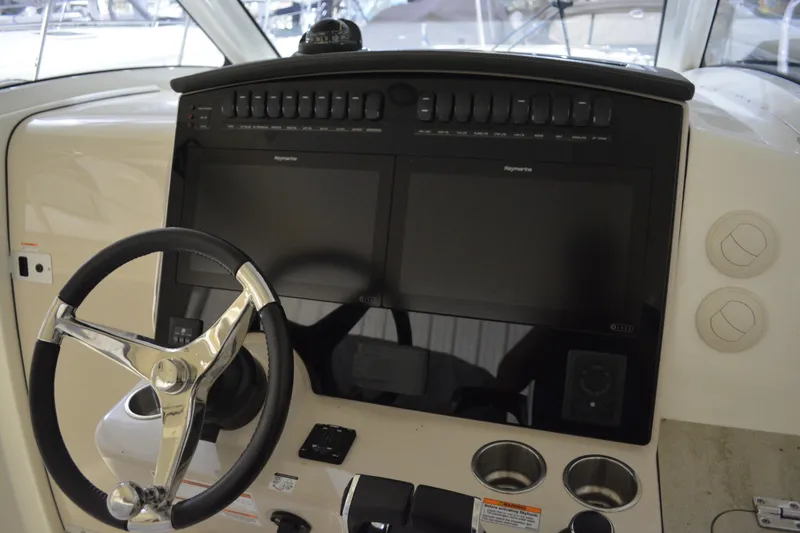 Slide: The Image of 2019 Boston Whaler 350 Realm dashboard with steering wheel and dual Raymarine displays. - 82