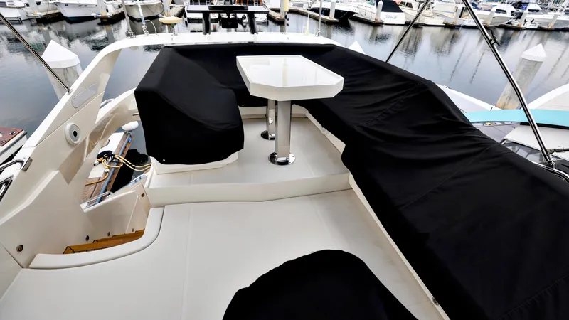 Slide: The Image of 2013 Marquis 500 Sport Bridge yacht deck with black seating covers and table, docked at marina. - 14