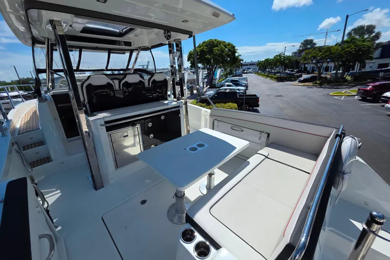 Slide: The Image of 2021 Jeanneau Leader 10.5 WA boat interior with sleek seating and table under blue sky. - 18