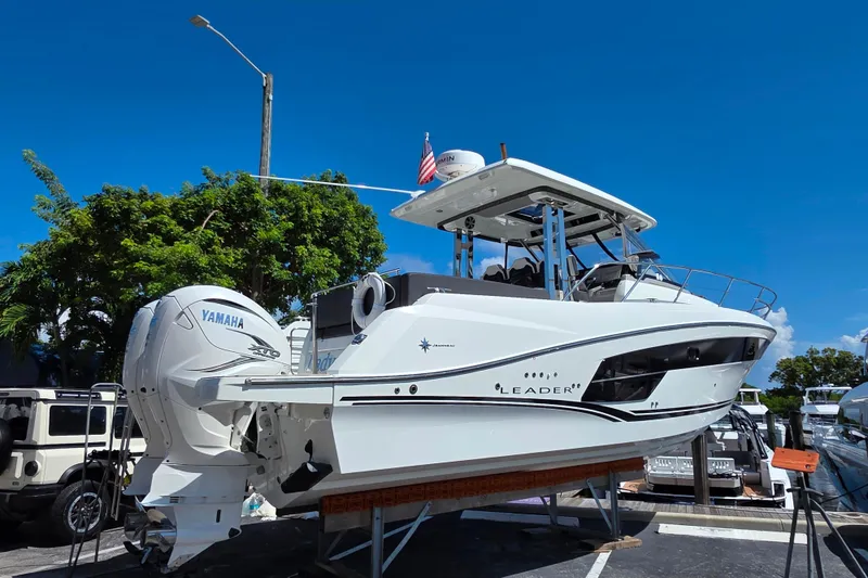 Slide: The Image of 2021 Jeanneau Leader 10.5 WA boat with twin Yamaha engines, docked under a clear sky. - 5