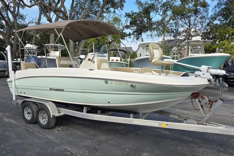 The Image of 2017 Stingray 206cc boat on trailer, parked outdoors with canopy and seating. - 1