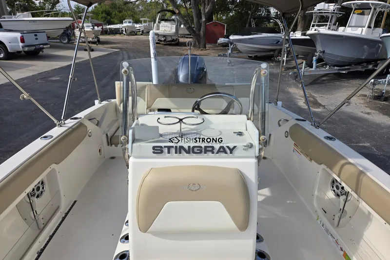Slide: The Image of 2017 Stingray 206cc boat interior with steering wheel and seating, parked in a marina. - 11