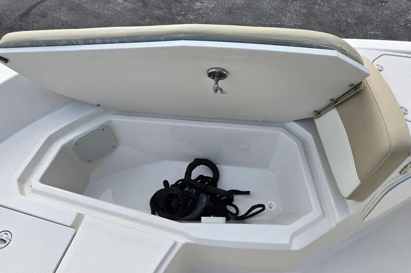 Slide: The Image of 2017 Stingray 206cc boat storage compartment with open lid and coiled rope inside. - 22