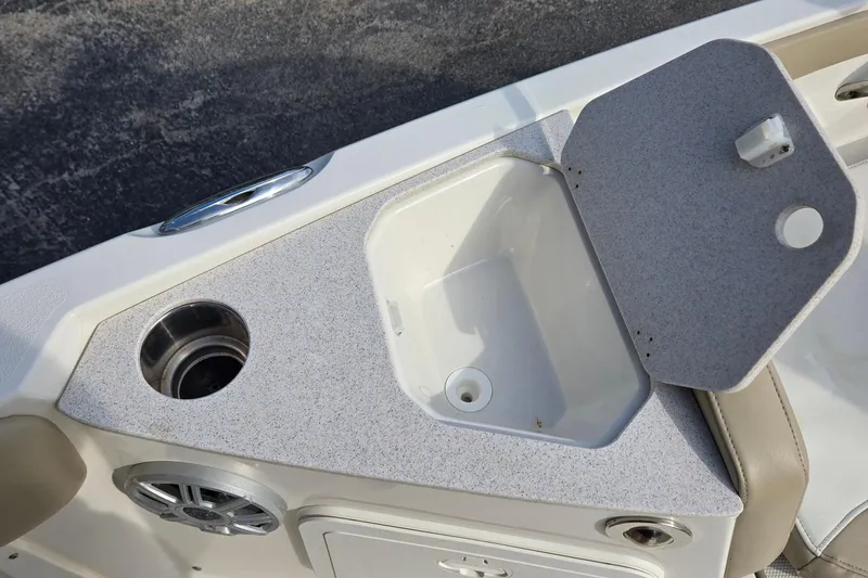 Slide: The Image of 2017 Stingray 206cc boat interior with open storage compartment and cup holder. - 24