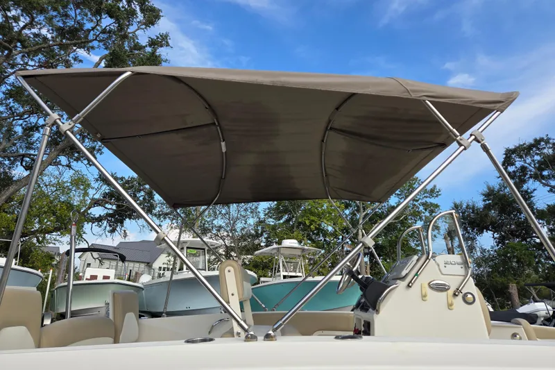 Slide: The Image of 2017 Stingray 206cc boat with canopy, steering console, and clear blue sky background. - 25