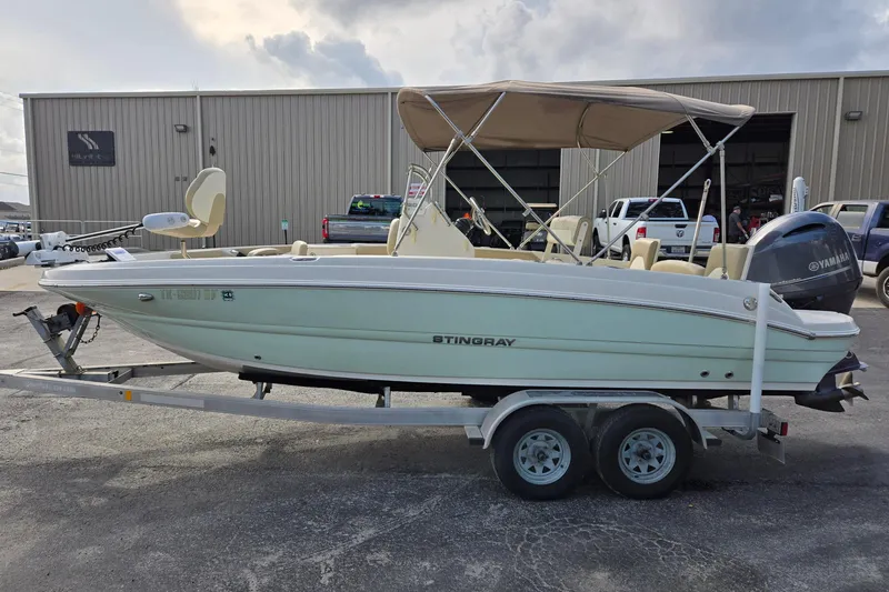 Slide: The Image of 2017 Stingray 206cc boat on trailer, parked outside a warehouse. - 6