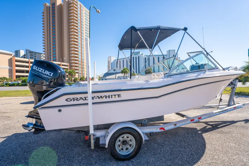 Slide: The Image of 1999 Grady-White Tournament 192 boat on trailer with Suzuki engine, urban backdrop. - 5