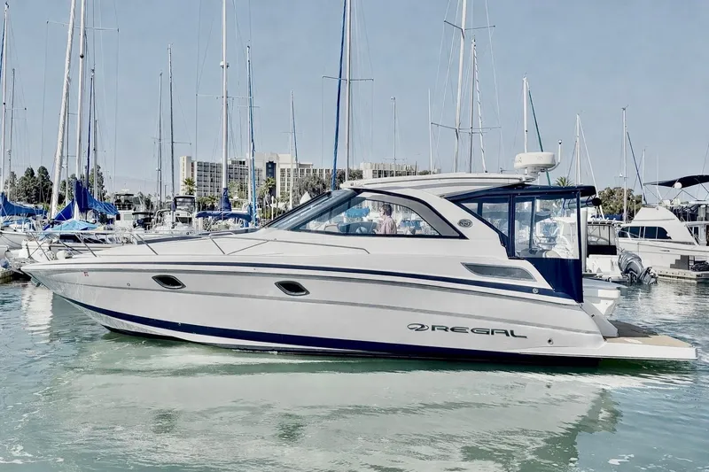 Slide: The Image of 2017 Regal 35 Sport Coupe yacht docked in a marina, surrounded by sailboats. - 0