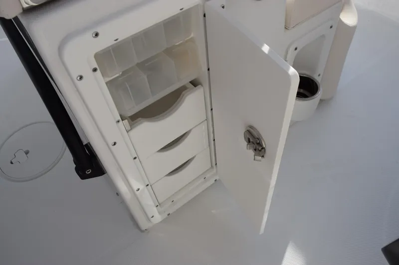 Slide: The Image of 2026 Sea Hunt Ultra 255 SE boat storage compartment with open door and organized shelves. - 14