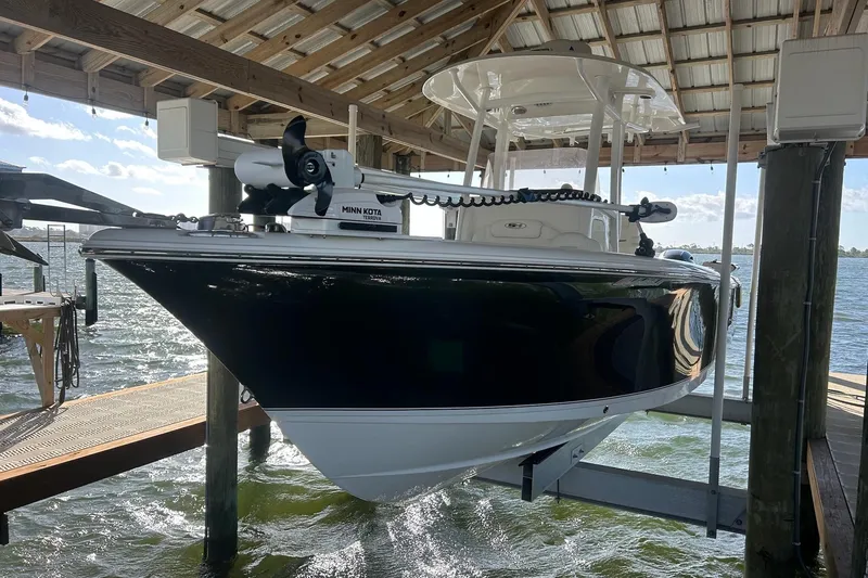 Slide: The Image of 2015 Sea Hunt Gamefish 25 boat on lift under dock, equipped with Minn Kota motor. - 2