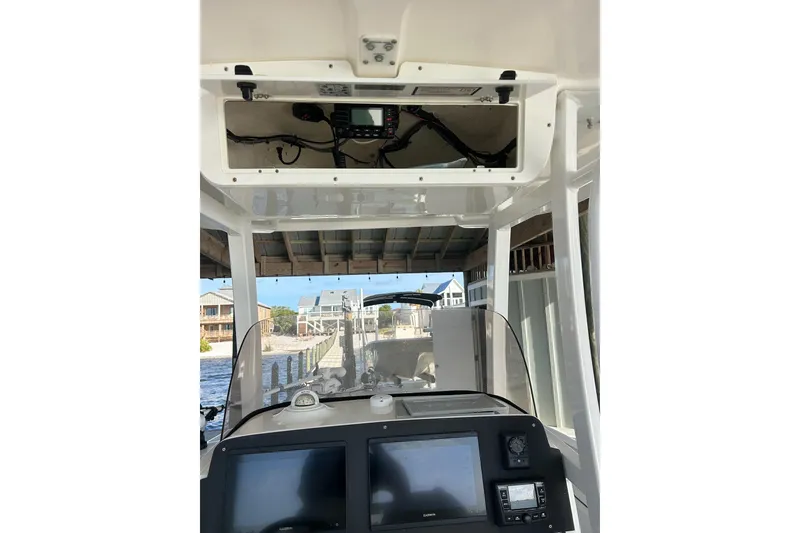 Slide: The Image of 2015 Sea Hunt Gamefish 25 boat dashboard with navigation equipment and open storage compartment. - 25