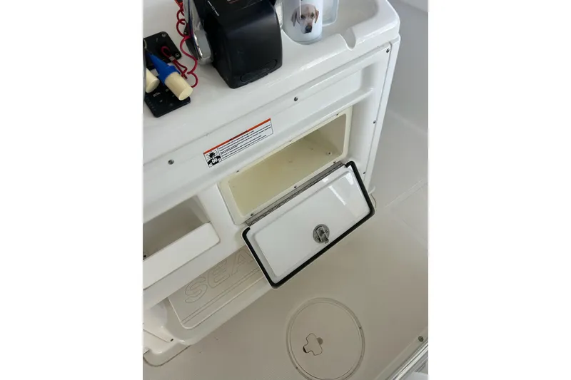 Slide: The Image of 2015 Sea Hunt Gamefish 25 boat storage compartment with open hatch and control panel. - 26