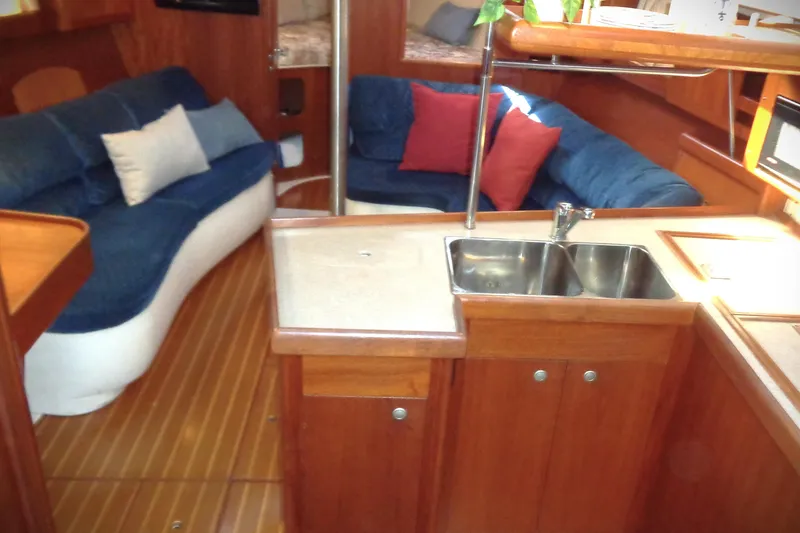 Slide: The Image of Interior of 2001 Hunter 380 sailboat with wooden cabinetry and blue cushioned seating. - 12
