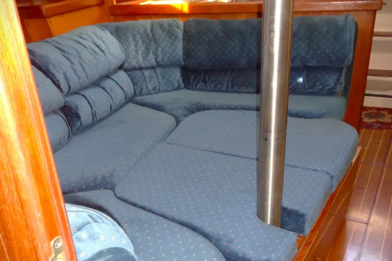 Slide: The Image of Interior of 2001 Hunter 380 sailboat with wooden table and blue cushioned seating. - 4