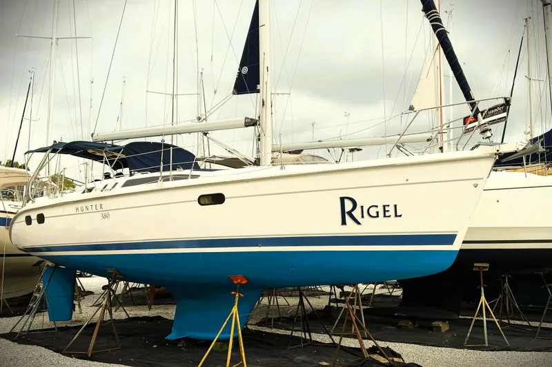Slide: The Image of 2001 Hunter 380 sailboat "Rigel" on stands, white hull with blue accents. - 1
