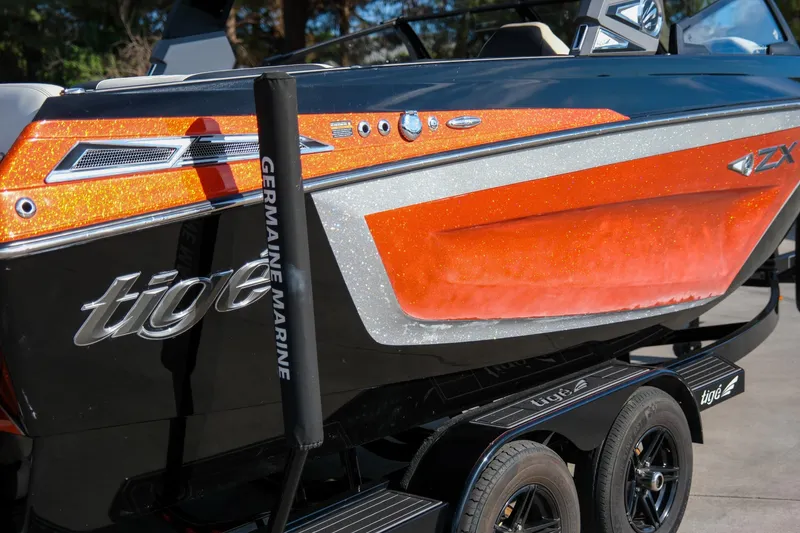 Slide: The Image of 2021 Tigé 21ZX boat with orange and black design on a trailer. - 10