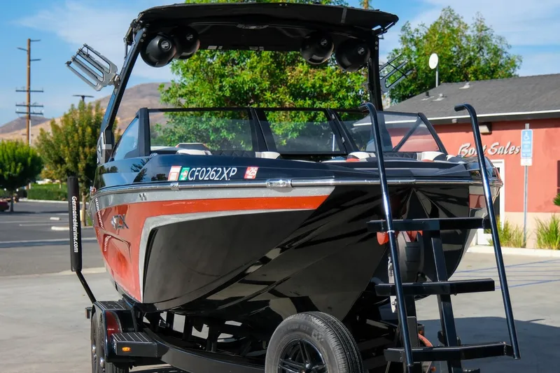 Slide: The Image of 2021 Tigé 21ZX boat on trailer, vibrant orange and black design, parked outdoors. - 12