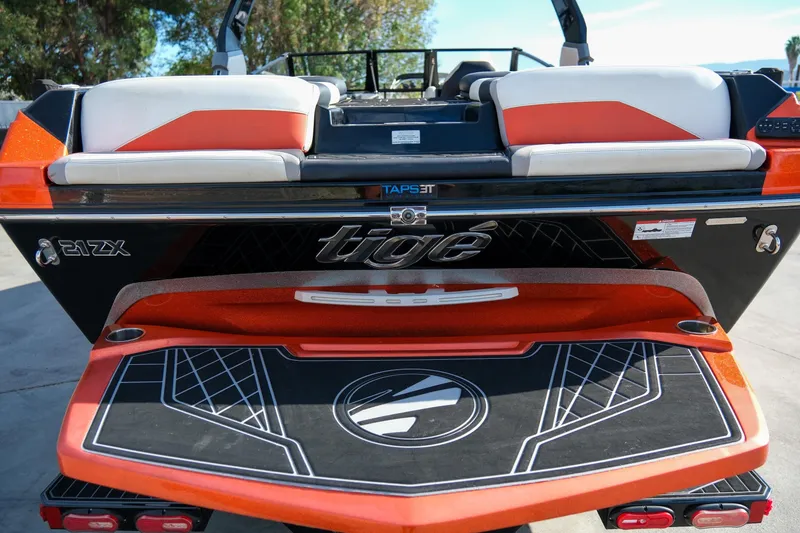 Slide: The Image of 2021 Tigé 21ZX boat rear view with orange and black detailing. - 27