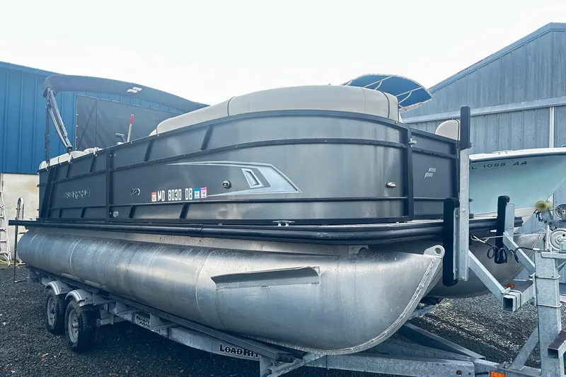 The Image of 2019 Starcraft 2210 OB Limited pontoon boat on trailer, parked near blue building. - 0