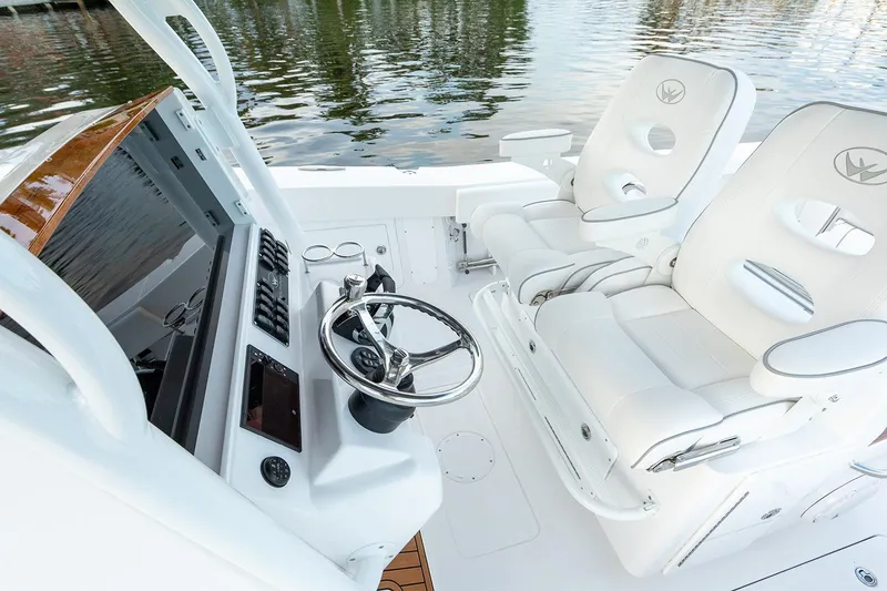 Slide: The Image of Manufacturer Provided Image: 2025 Southport 30 FE boat cockpit with white seating and steering wheel, docked by water. - 6