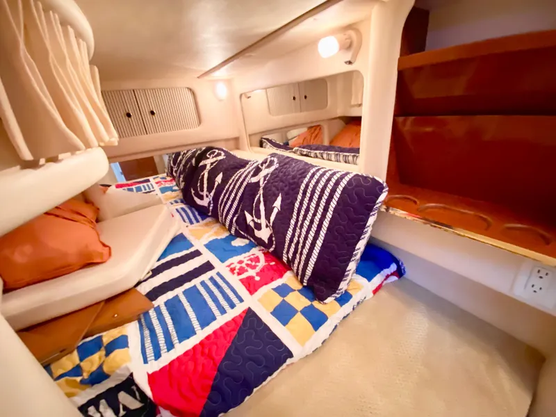 Slide: The Image of Cozy cabin interior of 2001 Sea Ray 290 Sundancer with nautical-themed bedding. - 14