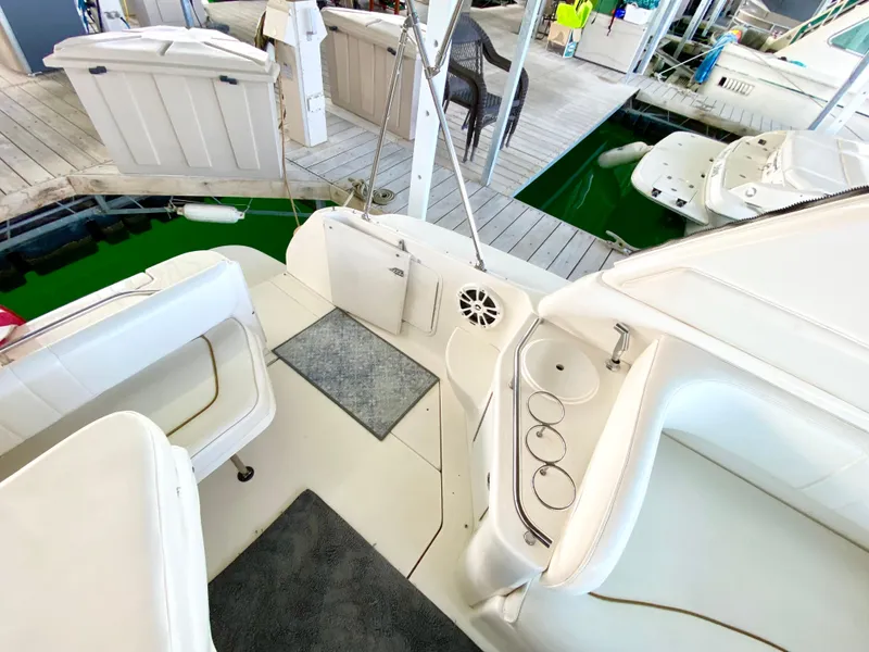 Slide: The Image of 2001 Sea Ray 290 Sundancer boat interior with seating and cup holders at a marina. - 23