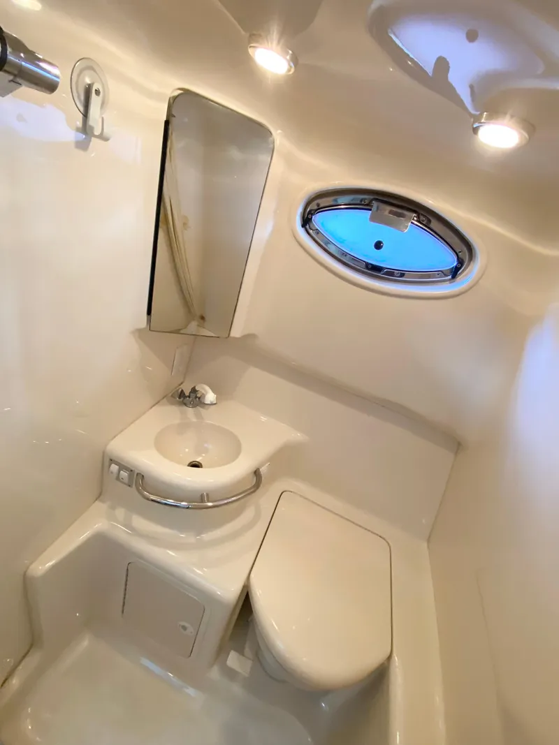 Slide: The Image of 2001 Sea Ray 290 Sundancer bathroom with sink, toilet, and porthole window. - 9