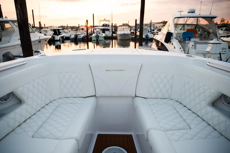Slide: The Image of Manufacturer Provided Image: 2025 Southport 33 DC boat interior with white seating, docked at marina during sunset. - 7