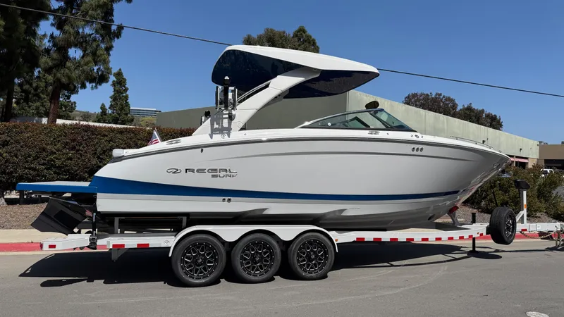 Slide: The Image of 2025 Regal LS9 Surf boat on trailer, parked outdoors, side view. - 11